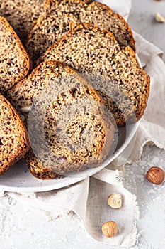 Sliced hazelnuts and banana loaf cake on a ceramic plate.