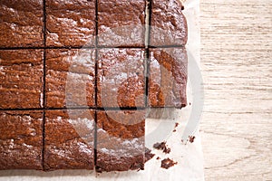 Sliced homemade brownies. On paper baking over wooden table. Top