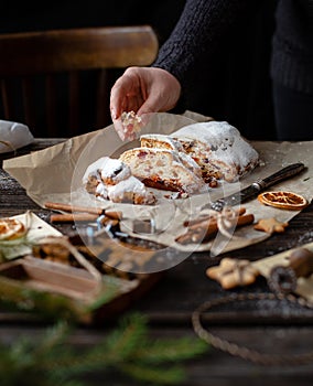 Sliced homemade Christmas dessert stollen with dried berries and nuts on parchment in woman hand