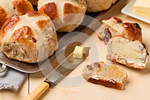 Sliced hot cross bun and knife with butter