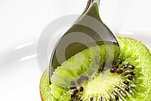 Sliced kiwi fruit with a metal spoon