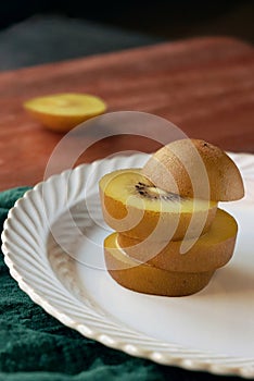 Sliced kiwi fruit on a white plate, close-up of golden kiwi fruit