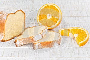 Sliced lemon cake with some fresh orange fruits on a wooden table