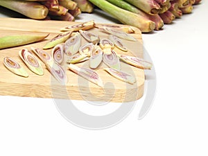 Sliced lemon grass on a wooden cutting board on white background.