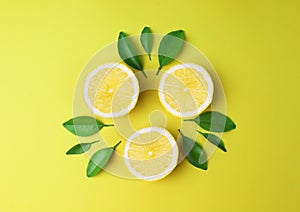 Sliced lemon with green leaf on yellow background