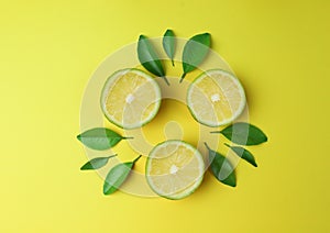 Sliced lime lemon with green leaf on yellow background