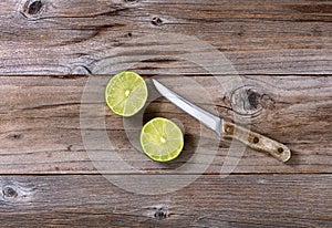 Sliced lime and paring knife on rustic wood in flat lay format