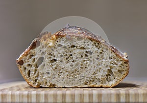 Sliced loaf of artisanal whole wheat and dark rye rustic sourdough bread on a cutting board, baked at home, photo series