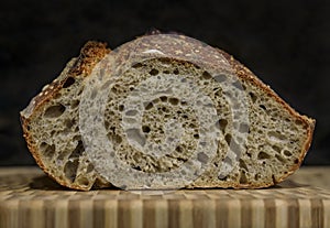 Sliced loaf of artisanal whole wheat and dark rye rustic sourdough bread on a cutting board, baked at home, photo series