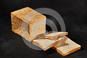 Sliced loaf of fresh, palatable baked white bread against black background with copy space. Close-up