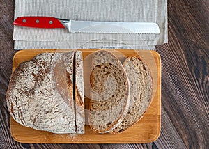 Sliced loaf of rye bread with a knife on a cutting board