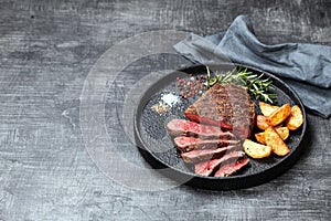 Sliced medium rare grilled beef steak and potato wedges photo