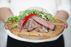 Sliced medium rare grilled Beef steak Ribeye in hands of a woman