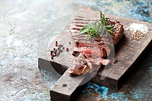 Sliced medium rare grilled beef steak on wooden cutting board