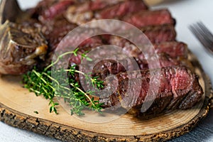 Sliced medium rare grilled beef steak on wooden cutting board with spices