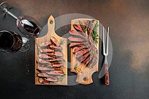 Sliced medium rare grilled steak with red wine on cutting board with rosemary and spices