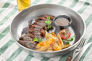 Sliced medium rare grilled Steak Ribeye with french fries and glass of beer on the table