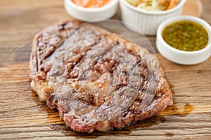 Sliced medium rare grilled Steak Ribeye with Pickled cabbage and two sauces. Serving on a wooden Board. Barbecue