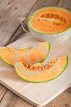 Sliced of melon on wood board.