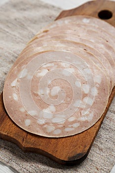 Sliced Mortadella Bologna Meat on a rustic wooden board, low angle view. Close-up