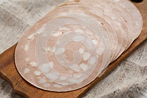 Sliced Mortadella Bologna Meat on a rustic wooden board, side view. Closeup