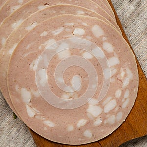 Sliced Mortadella Bologna Meat on a rustic wooden board, top view. Flat lay, overhead, from above. Closeup