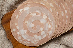 Sliced Mortadella Bologna Meat on a rustic wooden board, view from above. Flat lay, top view, overhead