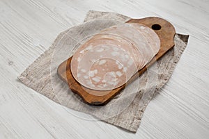 Sliced Mortadella Bologna Meat on a rustic wooden board on a white wooden background, low angle view