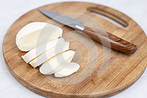 Sliced Mozarella cheese on the round wooden board