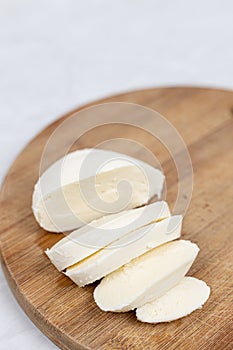 Sliced Mozarella cheese on the round wooden board