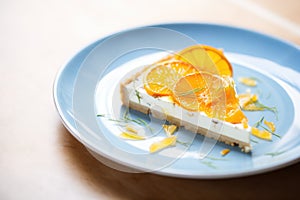 sliced orange cheesecake on plate, citrus zest garnish