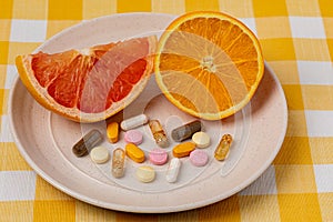 Sliced orange and grapefruit on plate with vitamins and dietary supplements.
