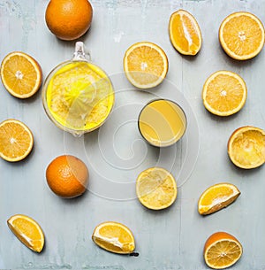 Sliced oranges, a juicer, a glass of juice wooden rustic background top view close up