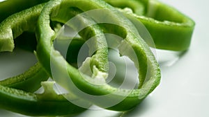 Sliced organic green bell peppers on a white ceramic plate close up.