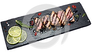 Sliced Organic grilled Tuna fillet covered with sesame seeds on black stone serving board