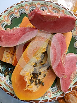 sliced papaya and guava on a patterned ceramic plate