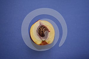 Sliced peach slice with pit on a blue background. Useful fruits close-up