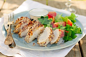 Sliced peanut crusted chicken breast with fresh salad