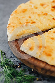 Sliced pie with cheese on a wooden board on grey background. Khachapuri