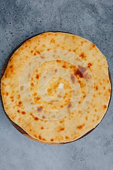 Sliced pie with cheese on a wooden board on grey background. Khachapuri