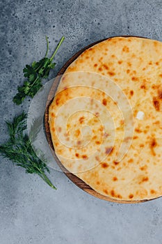 Sliced pie with cheese on a wooden board on grey background. Khachapuri