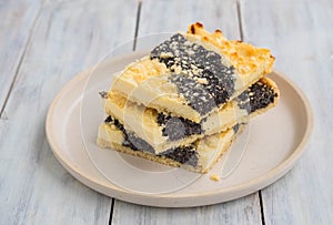 Sliced pie with cottage cheese and poppy filling on shortcrust pastry on a ceramic plate on a light wooden background. Poppy pies