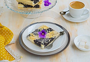 Sliced pie with cottage cheese and poppy filling on shortcrust pastry on a ceramic plate on a light wooden background. Poppy pies