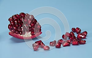 Sliced piece of pomegranate with seeds on blue background