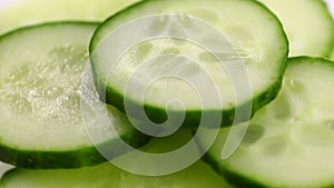 Sliced pieces of green cucumber stacked on a hill rotate counterclockwise, spinning slowly in a circle, close up.