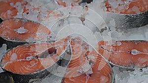 Sliced pieces of red fish salmon lie on ice in refrigerator freezer in store. Sturgeon, trout or chum keta. Seafood on