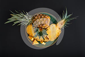 Sliced Pineapple. Bromelain whole pineapple tropical summer fruit halves pineapple black dark background on green plate