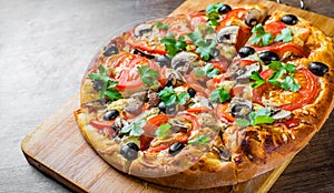 Sliced Pizza with Mozzarella cheese, Tomatoes, pepper, olive, mushrooms, Spices and Fresh leaf. Italian pizza on wooden table