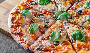 Sliced Pizza with Mozzarella cheese, Tomatoes, pepper, olive, Spices and Fresh Basil. Italian pizza. Pizza Margherita or Margarita