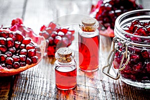 Sliced pomegranate and extract in glass on wooden background